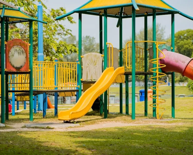 The exterior of a single-story daycare building with a fenced outdoor play area and colorful signage, in a natural documentary style.