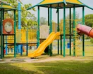 The exterior of a single-story daycare building with a fenced outdoor play area and colorful signage, in a natural documentary style.
