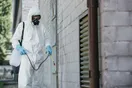 A pest control technician stepping out of a branded service truck in a suburban neighborhood, natural documentary style.