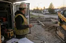 A site contractor at the open doors of a freshly equipped work vehicle in early-morning light, keys in hand, in a natural documentary style.