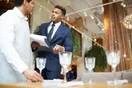 A caterer loading covered chafing dishes and trays into a van for an off-premise event, in a natural documentary style.