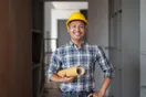 A general contractor in a hard hat reviewing framing plans on a residential job site, natural documentary style.