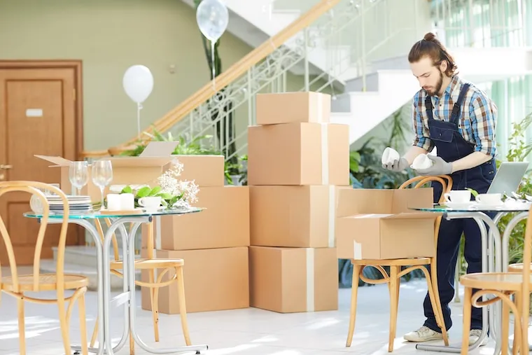 Two movers in matching shirts loading a wrapped sofa into a box truck on a residential street, in a natural documentary style.