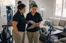 A cleaning business owner walking a new hire through a checklist on a clipboard, in a natural documentary style.