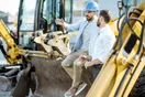 A landscaping crew leader showing a new hire how to operate a commercial mower on a residential lawn, in a natural documentary style.