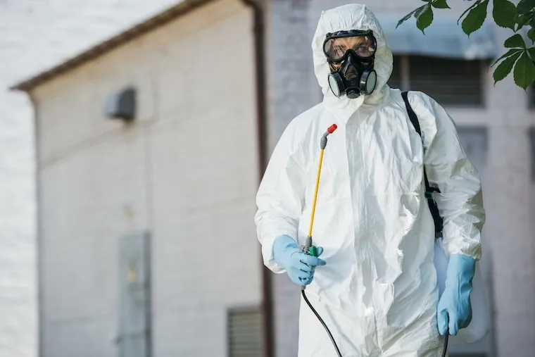 A pest control owner at a kitchen table with a laptop, a startup budget spreadsheet, and a calculator, in a natural documentary style.