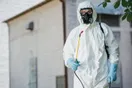 A pest control owner at a kitchen table with a laptop, a startup budget spreadsheet, and a calculator, in a natural documentary style.