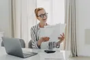 An accountant reviewing a profit-and-loss statement on screen with charts and a calculator on the desk, in a natural documentary style.