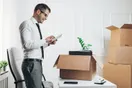 A moving company owner reviewing monthly job numbers on a tablet in front of a parked box truck, in a natural documentary style.