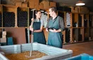 Guests tasting wine at a busy tasting room bar while a staff member pours, in a natural documentary style.