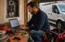 An electrician studying a metrics dashboard on a laptop in natural light, in a natural documentary style.