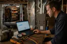 An HVAC technician studying a metrics dashboard on a laptop in natural light, in a natural documentary style.