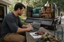 A junk removal operator studying a metrics dashboard on a laptop in natural light, in a natural documentary style.