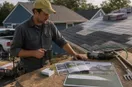 marketing materials, business cards, and a yard sign laid out on a workbench, in a natural documentary style.