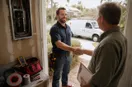 An electrician shaking hands with a homeowner at the front door, in a natural documentary style.