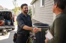 An HVAC technician shaking hands with a homeowner at the front door, in a natural documentary style.