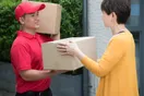 A delivery business owner shaking hands with a shop manager at a retail counter beside parcels, in a natural documentary style.