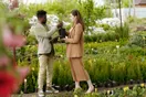 A landscaper handing a flyer to a homeowner at their front door on a suburban street, in a natural documentary style.