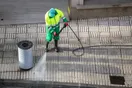 A pressure washing operator hanging a door-hanger flyer on a suburban front door with a work truck at the curb, in a natural documentary style.