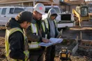 A site contractor prepping two work vehicles with crew members at sunrise, in a natural documentary style.