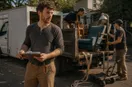 A junk removal operator prepping two work vehicles with crew members at sunrise, in a natural documentary style.