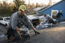 A roofing contractor prepping two work vehicles with crew members at sunrise, in a natural documentary style.
