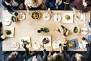 A catering crew in matching uniforms plating multiple dishes on a stainless prep line before an event, in a natural documentary style.
