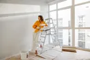 A painting crew of three loading ladders and sprayers into a branded work van in the morning, in a natural documentary style.