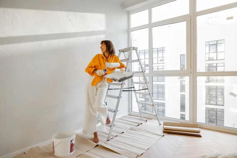 A painting crew of three loading ladders and sprayers into a branded work van in the morning, in a natural documentary style.