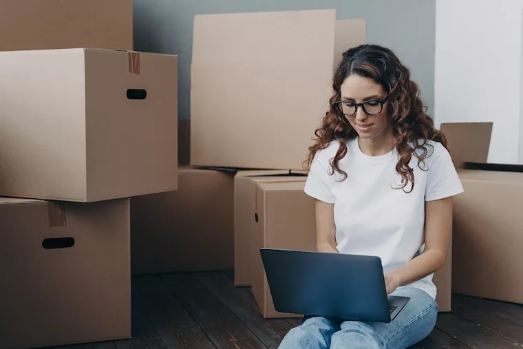 A designer sketching moving company logo concepts with a box truck reference photo on the desk, natural documentary style.