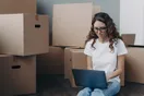 A designer sketching moving company logo concepts with a box truck reference photo on the desk, natural documentary style.