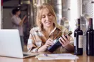 A designer's desk with wine label sketches, color swatches, and a bottle mockup under focused light, in a natural documentary style.