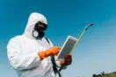 A pest control website homepage open on a smartphone held in a home office, documentary style.