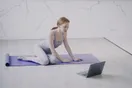 A yoga studio schedule and class booking page open on a laptop and a phone side by side, in a natural documentary style.