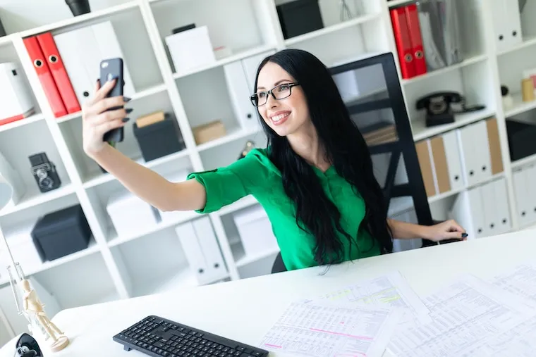 A phone on a desk showing an accounting firm's Instagram grid of tax-tip carousels, next to a laptop and coffee, documentary style.