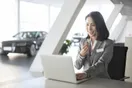 A salesperson filming a walkaround video of a used car on the lot with a phone on a gimbal, in a natural documentary style.
