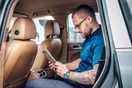 A person browsing a Facebook feed on a phone showing a car rental ad with vehicle photos, documentary style.