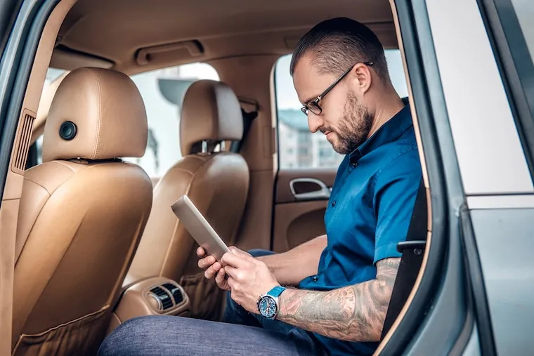 A person browsing a Facebook feed on a phone showing a car rental ad with vehicle photos, documentary style.