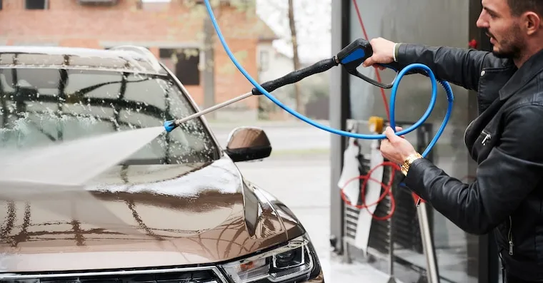 A car being filmed on a smartphone gimbal as it moves through a tunnel car wash, in a natural documentary style.