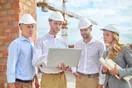 A construction contractor reviewing a Facebook page of completed projects on a phone at a job site, in a natural documentary style.