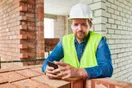 A contractor filming himself on a phone at a framing jobsite for a TikTok video, shot in a plain documentary style.