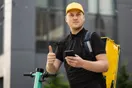 A delivery business owner reviewing a Facebook ad on a laptop beside a stack of packages, in a natural documentary style.