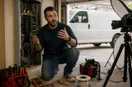 An electrician explaining a technique to an off-frame camera in the workshop, in a natural documentary style.