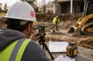 A phone on a small tripod filming a site contractor at work, in a natural documentary style.