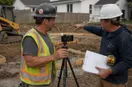 A phone tripod set up while a site contractor demonstrates equipment, in a natural documentary style.