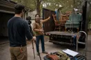 A phone tripod set up while a junk removal operator demonstrates equipment, in a natural documentary style.
