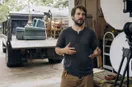 A junk removal operator explaining a technique to an off-frame camera in the workshop, in a natural documentary style.