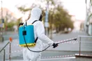 A pest control technician hanging a door hanger flyer on a suburban front door, documentary style.