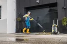 A pressure washing technician hanging a door hanger flyer on a suburban house in a neighborhood of similar homes, in a natural documentary style.