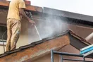 A phone on a tripod filming a pressure washer cleaning a stained driveway, showing a sharp line between dirty and clean concrete, in a natural documentary style.